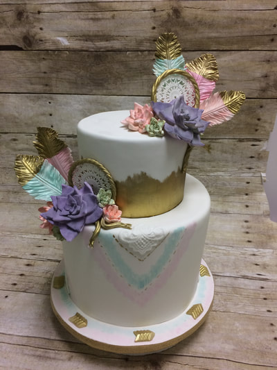 2 tier baby shower cake with gold tipped feathers.