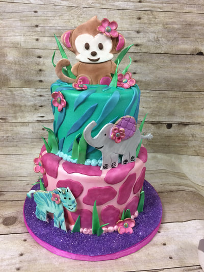 2 tier baby shower cake with animal cut outs and pink colors on bottom tier and green and blue colors on top.