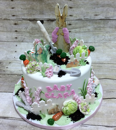 garden scene baby shower cake with a rabbit, garden tools made of chocolate, chocolate carrots, flowers