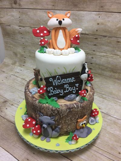 woodland themed baby shower cake with fox, owl and wolf on cake as well as bright red and white mushrooms. 2 tier with bottom tier looks like a log.