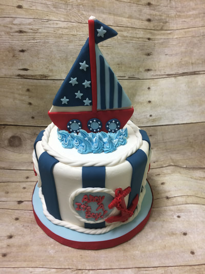 nautical theme baby shower cake. blue and white with a red white and blue sailboat on top.