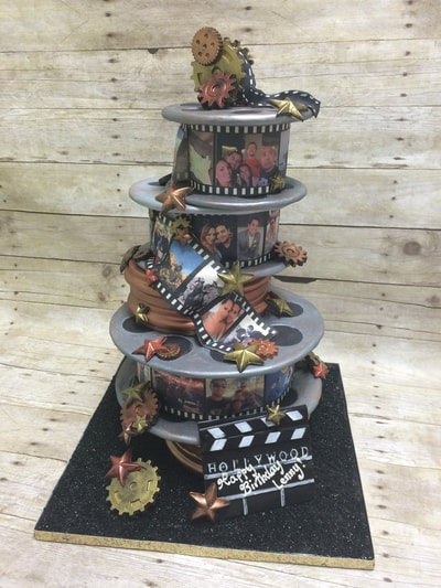 4 tier happy birthday novelty cake stacked like rolls of film. each frame showing a different picture of the family.