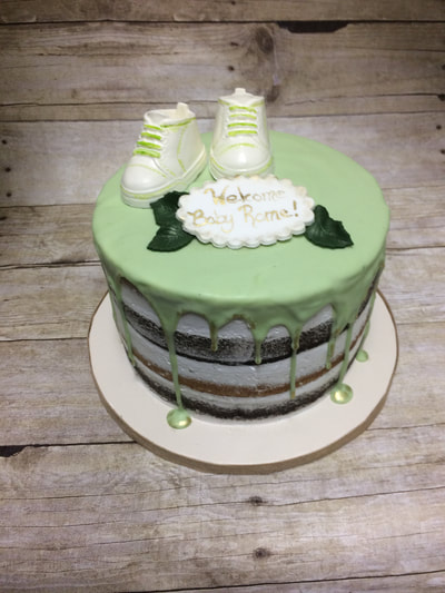 naked cake baby shower cake with light green drip icing and baby booties on top