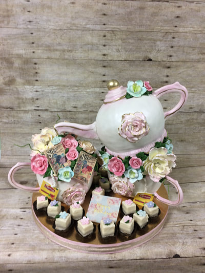 Tea party cake. With tea pot and tea cups made of cake with fondant icing. Lots of gumpaste flowers and a dozen petit fours.