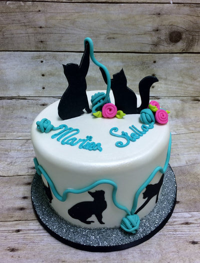 Single tier cake with silhouettes of cats playing with colored fondant balls of yarn