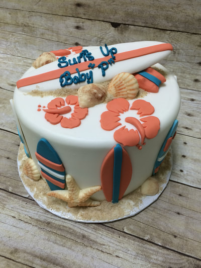 surfs up baby shower cake. single tier with chocolate surfboard on top and hibiscus flowers, chocolate sea shells.